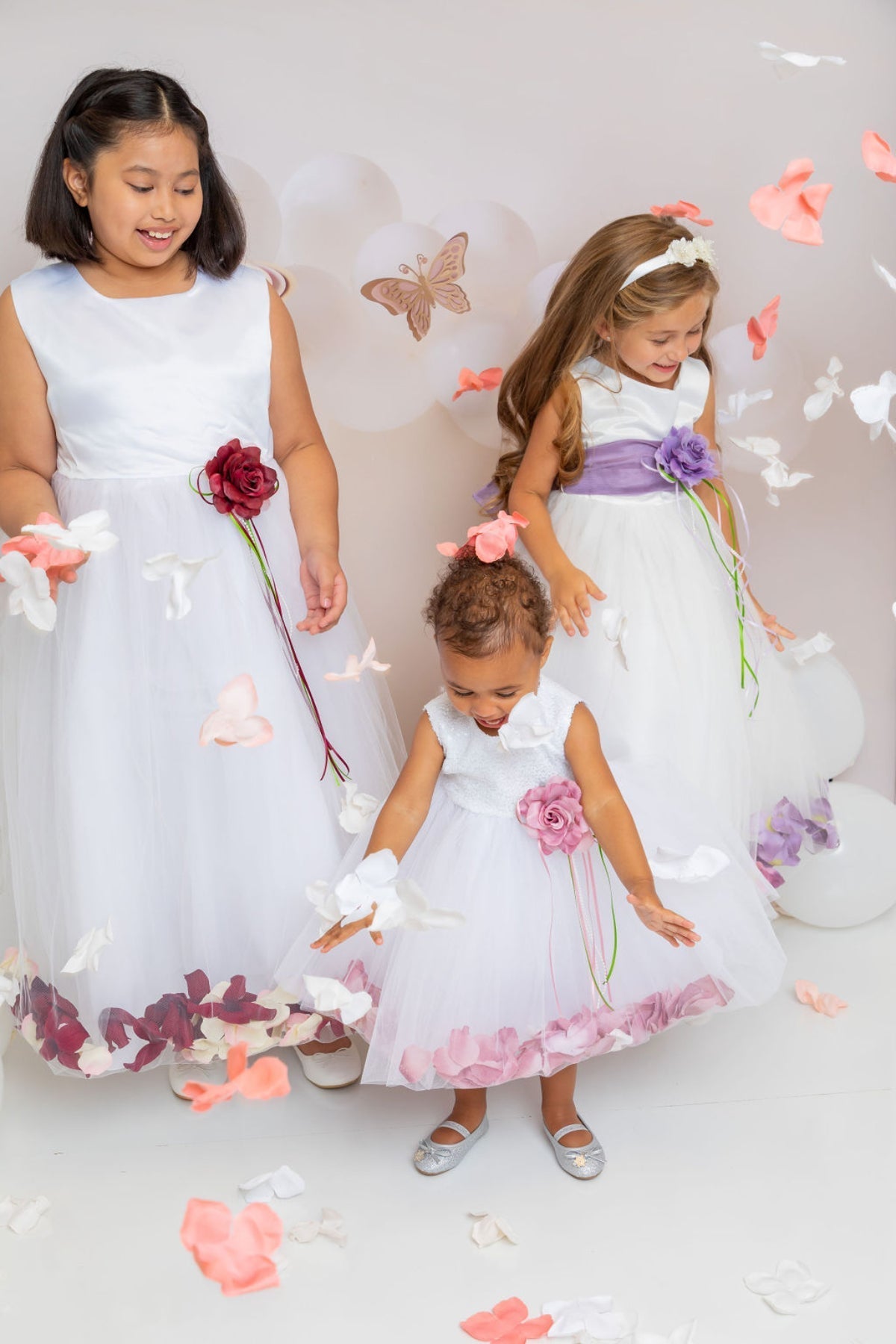 White satin flower petal girl dress with organza sash and floral embellishments, perfect for special occasions.