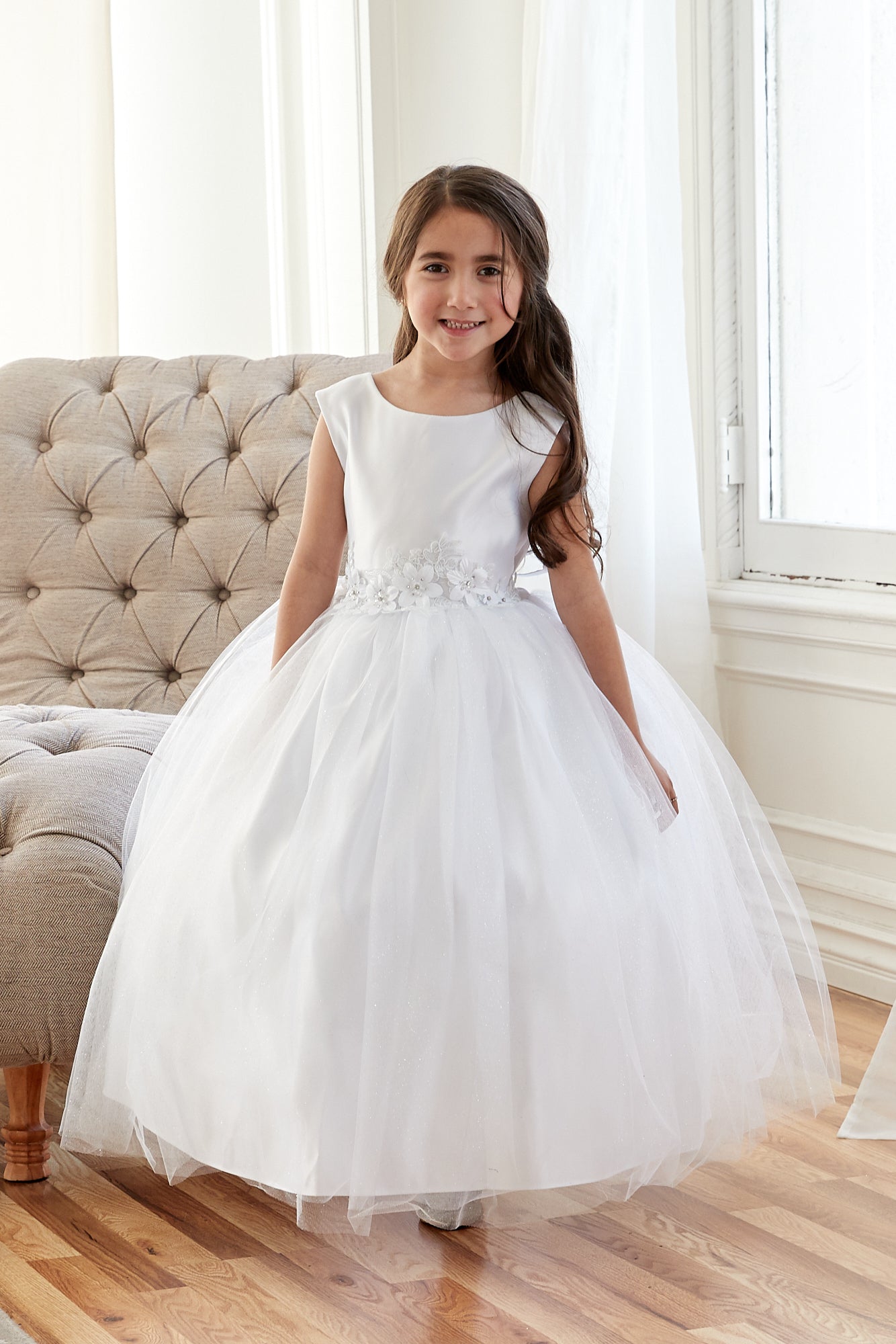 Sleeveless white tulle flower girl dress by Calla Collection with embellished rhinestone waist.